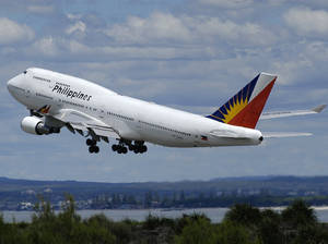 菲律賓航空波音747在熱帶海岸線上起飛。