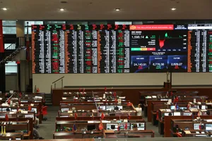 交易員在交易所的大型金融數據屏幕下於辦公桌前工作。