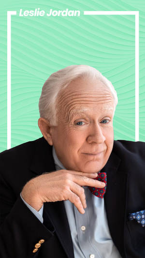 Leslie Jordan 身穿西裝打領結，背景為藍綠色。