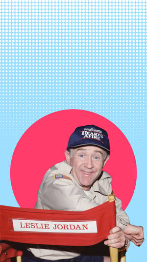 Leslie Jordan 喺導演椅上，背景有粉紅色圓圈同藍色半色調。