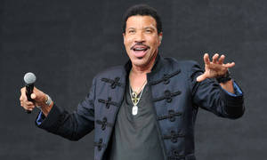 Lionel Richie 在舞台上用咪高峰唱歌，表情豐富。