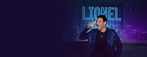Lionel Richie 在天台上微笑，身後有霓虹燈標誌。
