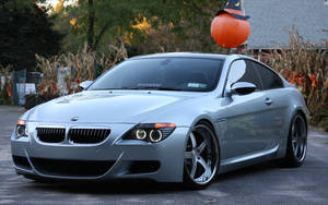 銀色BMW M6跑車在秋天停泊在萬聖節裝飾附近。