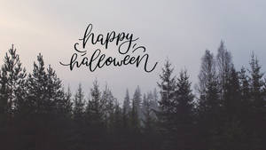 在霧氣籠罩的松樹林上方以草書顯示的 Happy Halloween 文字