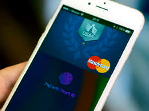 手拿著iPhone，顯示USAA MasterCard付款畫面及Touch ID提示。