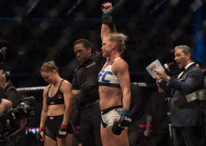 女性UFC拳手在八角籠中舉起拳頭慶祝勝利。