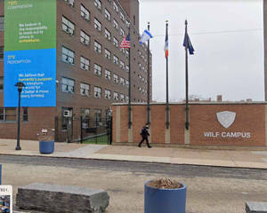 人走過 Wilf Campus 磚牆，帶有旗幟和標誌。