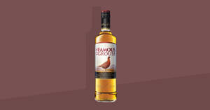 一瓶 The Famous Grouse 威士忌在栗色漸變背景上。