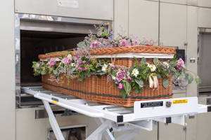 帶有花朵的柳條棺材在推車上被移入火化爐。 — 屍新娘 壁紙