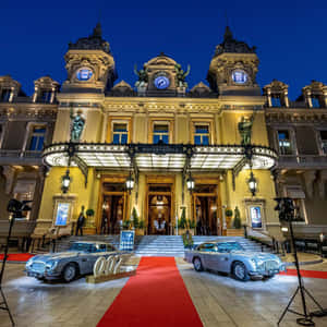 兩輛銀色Aston Martin DB5汽車在夜間停放在蒙地卡羅賭場前的紅地毯上。 — 平板電腦 壁紙