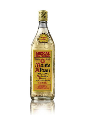 一瓶 Monte Alban mezcal，帶有龍舌蘭蟲標籤，放在白色背景上，有倒影。