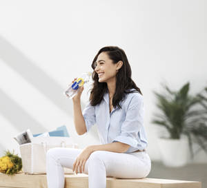 女子在明亮的房間裡坐在木長椅上喝smartwater瓶裝水 — 姬·加多 壁紙
