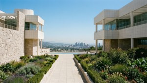 現代建築物配以石牆和花園，框出一條通往城市天際線的小徑。 — 洛杉磯 GIF 壁紙