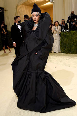 Rihanna 身穿黑色禮服和珠寶頭飾，在紅地毯活動中。