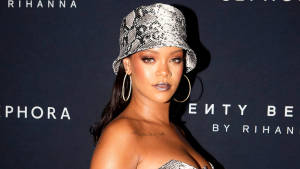 Rihanna 在 Fenty Beauty 活動中戴著銀色蛇皮水桶帽和圓環耳環。