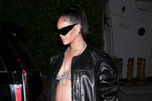 Rihanna 身穿黑色皮夾克和太陽眼鏡在夜晚戶外行走。