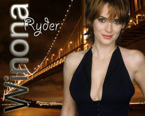 Winona Ryder 穿著黑色連衣裙，在夜間身後有燈光橋樑的情況下對著鏡頭微笑。 — 紐約市 壁紙