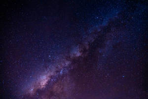 銀河系在黑暗的夜空中散發著紫色和藍色的星星。