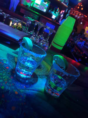 兩杯藍色發光瑪格麗特酒，配以青檸裝飾，在霓虹酒吧上。