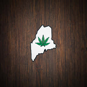 白色麻薩諸塞州輪廓別針，帶有綠色大麻葉，置於深色木上。 — iPad Pro 12.9 壁紙