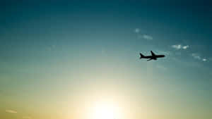 飛機剪影在漸變色彩的夕陽天空中飛行。 — 藍天 壁紙