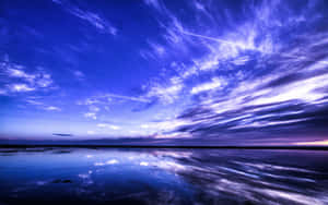 暮色中，平靜的水面倒映著紫藍色天空和雲彩。 — 藍天 壁紙