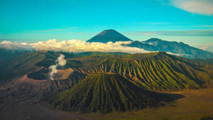 火山山脈，綠色的山坡，在藍天下，蒸氣從火山口升起。 — 藍天 壁紙