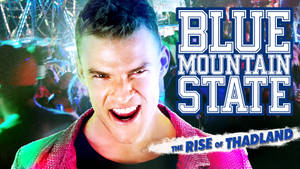 男子穿著粉紅色外套在夜間嘉年華上對著鏡頭微笑，帶有「Blue Mountain State」文字。