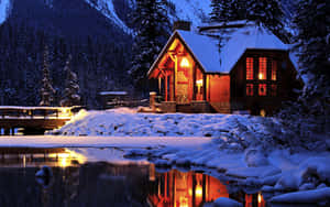 舒適的小屋，溫暖的燈光在夜間雪湖中倒映。 — 美學 壁紙