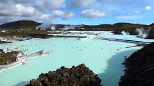藍綠色地熱池，人們在深色火山岩環繞下沐浴。