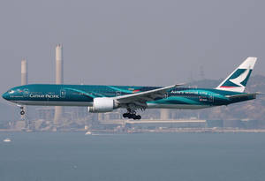 國泰航空飛機在工業煙囪附近的水面上降落。