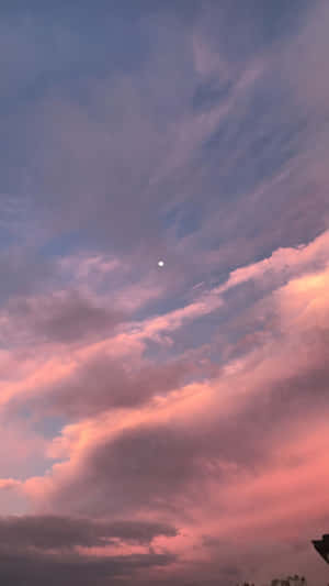 黃昏時的粉紅與紫色雲彩，上方有一輪小月亮