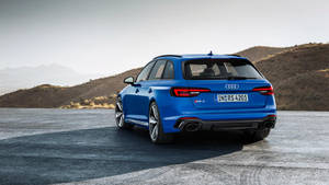 藍色奧迪RS4旅行車停泊在沙漠觀景點，背景有山脈。 — Audi R8 GIF 壁紙