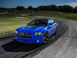 藍色 Dodge Charger R/T 在賽車場上，背景有綠草和樹木。