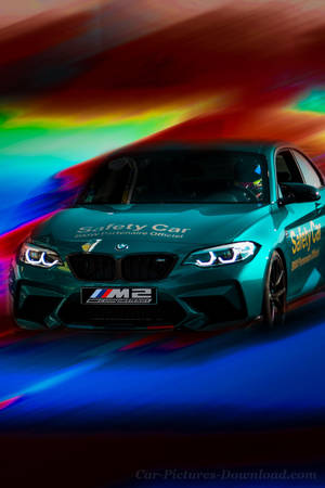 青綠色BMW M2安全車在彩虹動態模糊背景下加速行駛。 — 汽車 壁紙