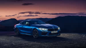 暮色中停在碎石上的藍色BMW M8 Coupe，背景為山脈。