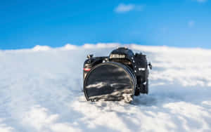 藍天下半埋在雪中的黑色Nikon相機