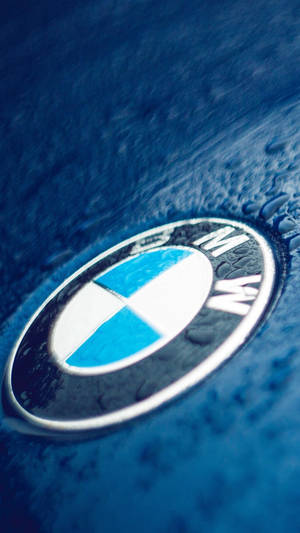 濕藍色引擎蓋上的 BMW 標誌，帶有水滴