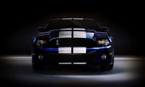 藍色 Shelby Mustang 帶有白色賽車條紋，在黑暗的工作室環境中照亮。