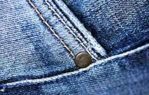 藍色牛仔布料的特寫，帶有縫線和金屬鈕扣。 — MacBook Air 13 壁紙