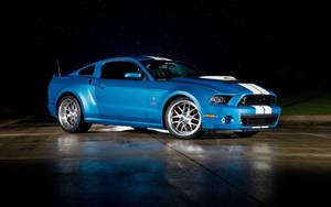 藍色Shelby Mustang帶白色條紋，夜間停在星空下潮濕的路面上。