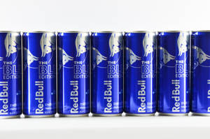 白色表面上的一排藍色Red Bull能量飲料罐。