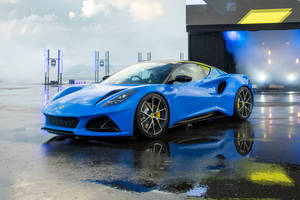 藍色蓮花跑車在潮濕的舞台上，薄霧和彩色燈光反射在地面上。 — 汽車 壁紙