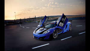日落時分，藍色McLaren跑車在賽道上敞開車門。