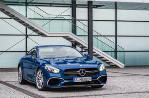 藍色 Mercedes 跑車停泊在現代玻璃建築物附近。