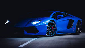 藍色林寶堅尼Aventador夜間停在帶有白色線條的瀝青路上。