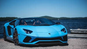 陽光明媚的日子裡，藍色林寶堅尼 Aventador SVJ 停泊在湖邊。