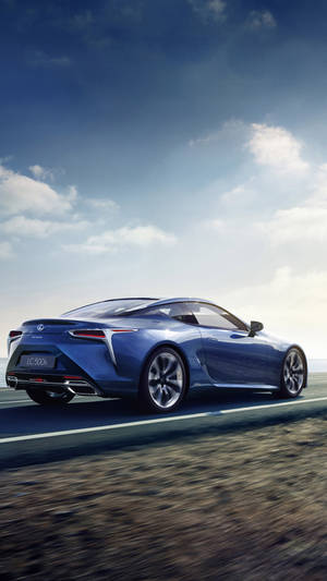 藍色Lexus LC 500在日落時分沿海岸高速公路飛馳。