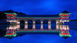 夜間在平靜水面上倒影的燈光璀璨傳統韓國橋樑。
