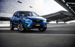 藍色Mazda CX-5 SUV停泊在現代鋼橋下。